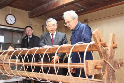 写真：知事(中央)に蛇胴製作の過程を説明する植田倫吉さん(右)