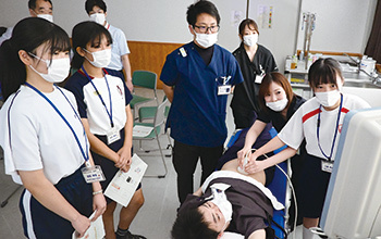 医師の指導を受けながらエコー検査を体験する中学生の写真