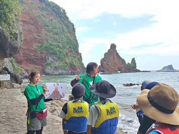 明屋海岸にてジオパークガイドの様子。