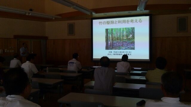 竹の駆除と利用を考える、についての報告の様子。スライドを使って研究内容を説明する研究員と聴講する参加者。