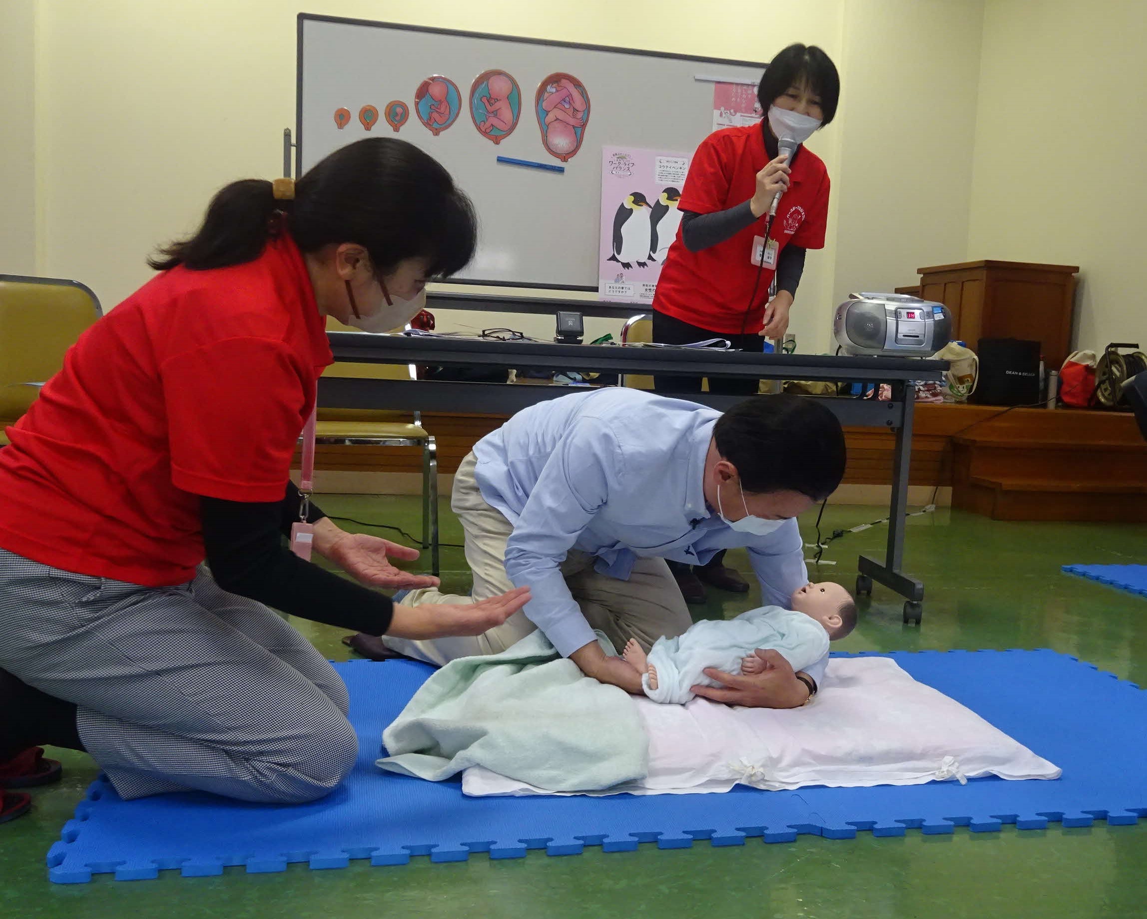 赤ちゃん人形を抱っこする知事