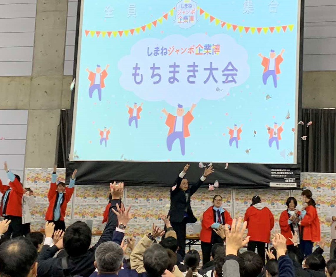 学生スタッフと一緒に餅まきをする知事