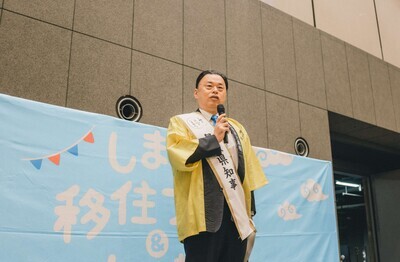 ステージから出展者の激励をする知事