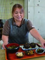 定食にアラメの炒め煮を添える是津益美さんの写真