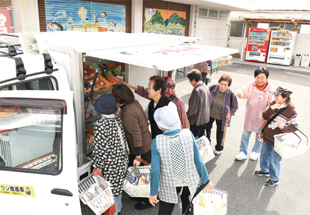 住民たちが移動販売車で生鮮食品などを品定めする様子