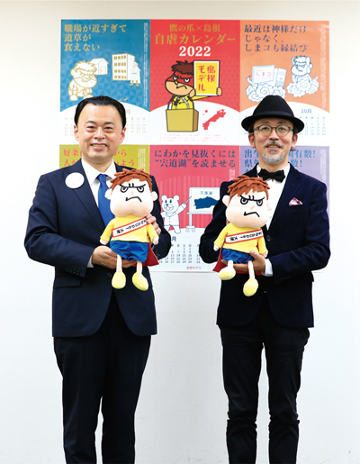 「吉田くん」のぬいぐるみを手にする小野亮氏（右）と丸山達也知事の写真