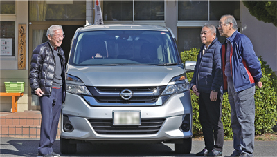 自治会輸送の車両の前で今後の取組を話す森山会長らの写真