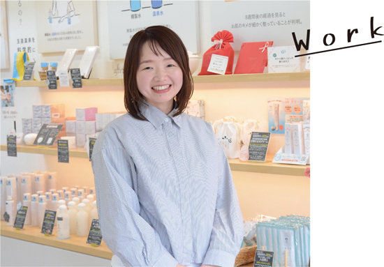 自社の商品の前でほほ笑む小林さんの写真