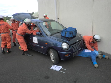 人が車の下敷きに