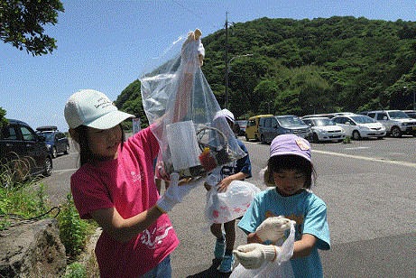 ごみ袋を持ち上げ、集めたごみを確認する子供たち