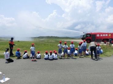 化学消防車のメインタレットからの放水を見学する弥栄小学校の写真