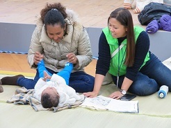 ベビーマッサージをする親子と通訳者の写真