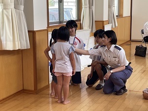 補導職員と職場体験の学生が園児に教えているようす